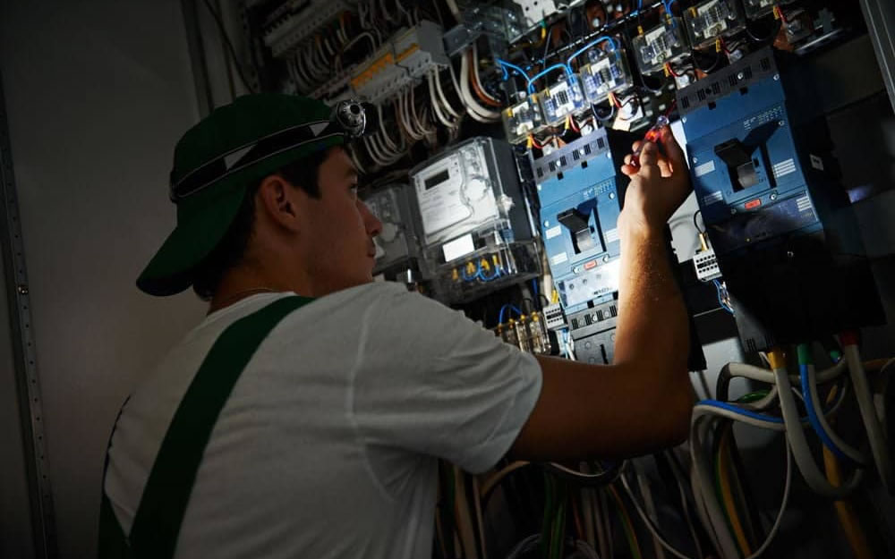 Certified electrician performing emergency electrical repair at night in California
